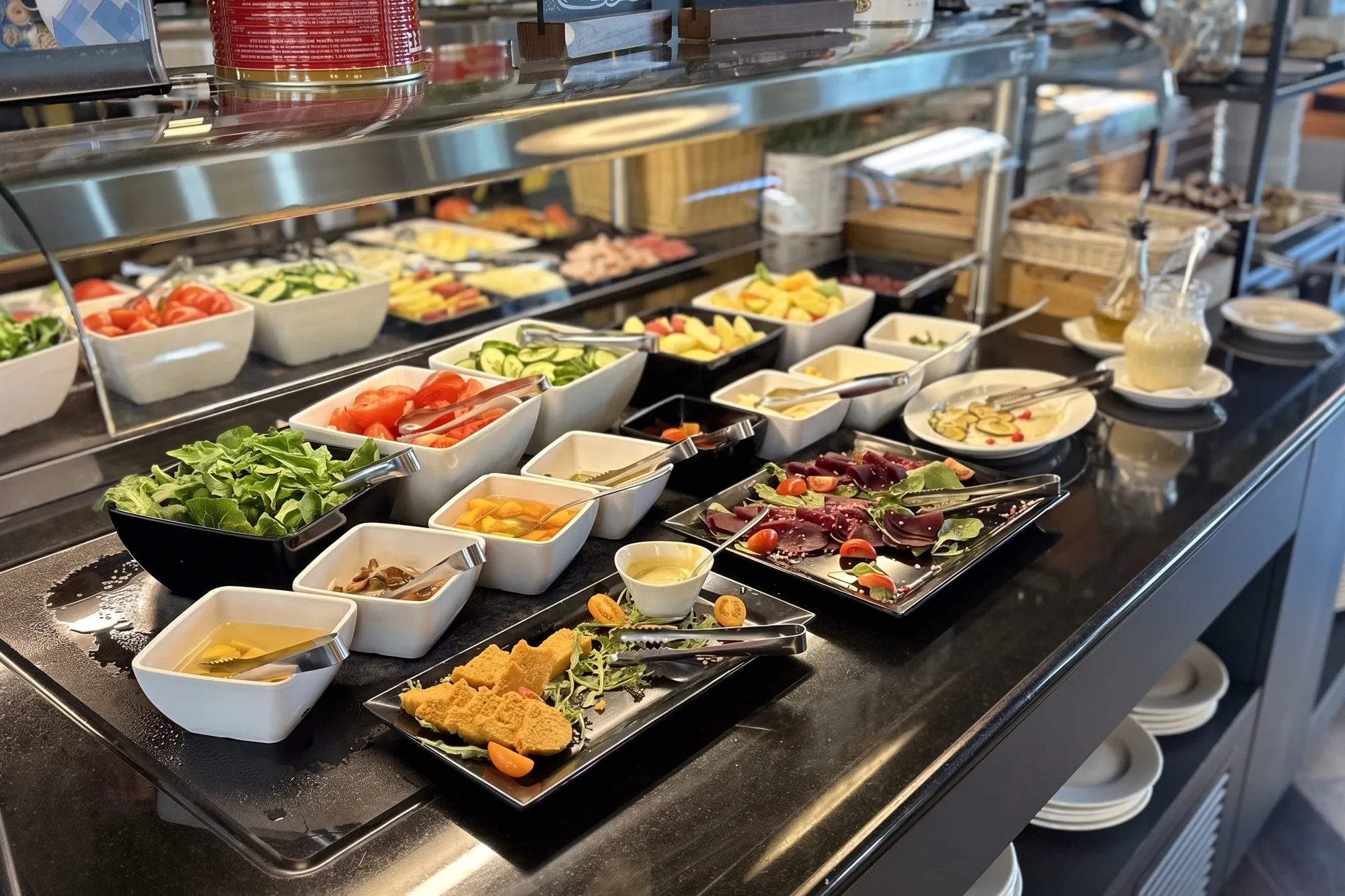Bufet śniadaniowy w restauracji o3eat w Warszawie — sałatki, warzywa, przystawki na zimno i sosy w białych miseczkach na ciemnym blacie